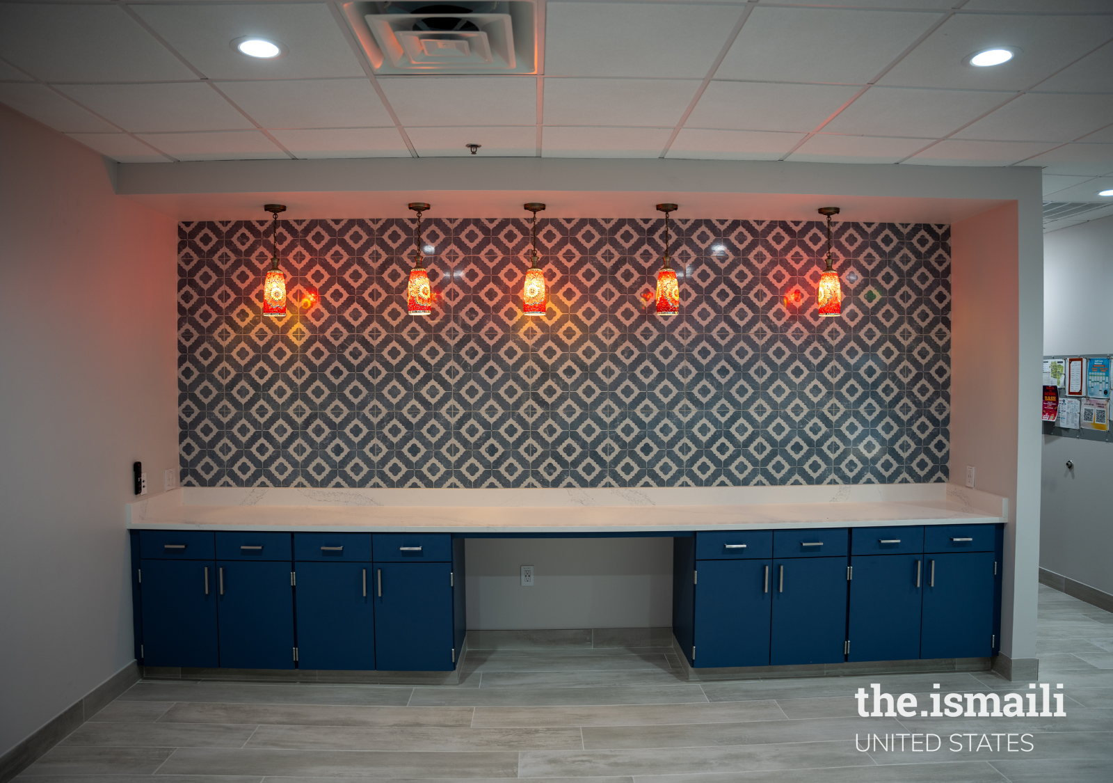 The back wall of Jamatkhana is a feature wall with geometrically patterned tiles and five imported Turkish pendant lights. In the center of the counter is a built-in desk space.