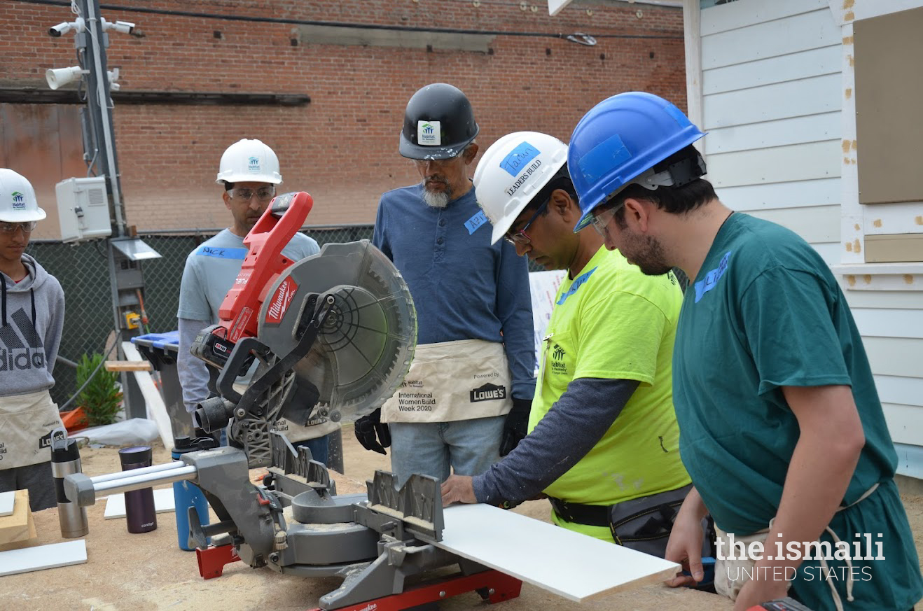 Cutting a piece of siding as Caleb and Naushad look on. Photo: Nimmi Richards.