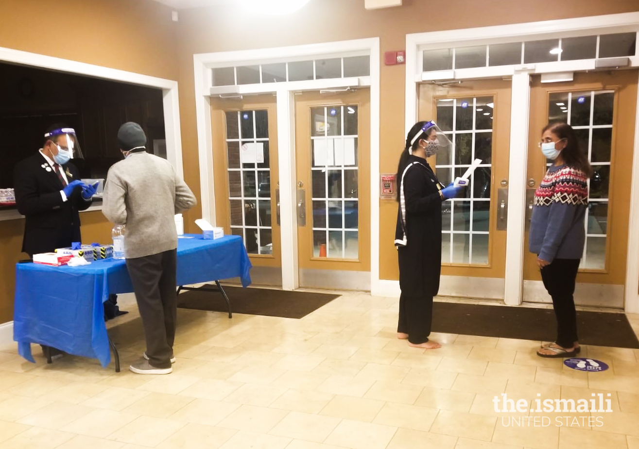 A volunteer in Atlanta South Jamatkhana performing a temperature check at the entrance.