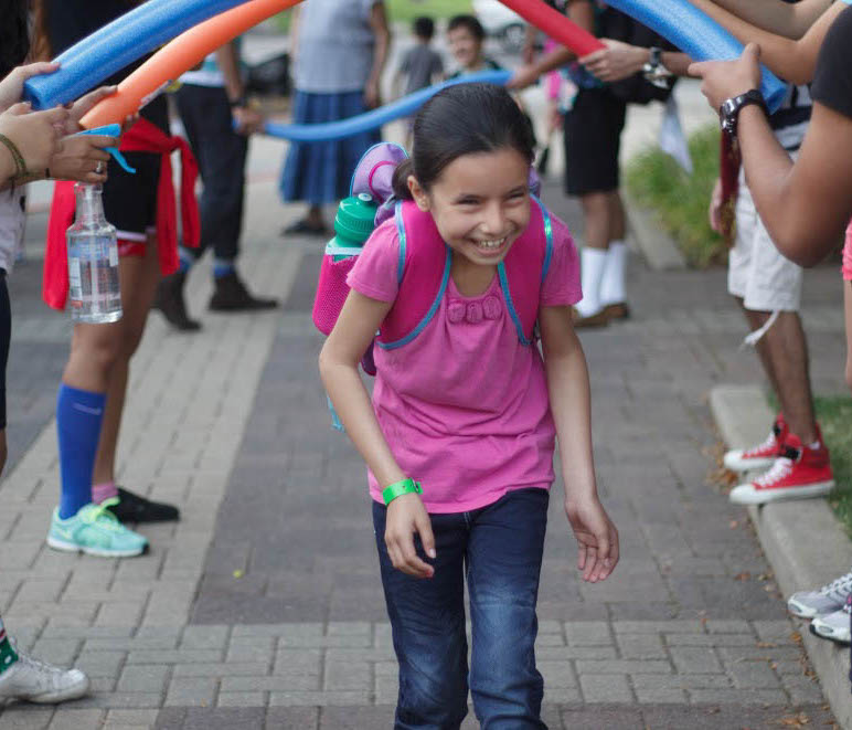 Walking through a tunnel of noodles, a participant smiles as she walks to her parents.