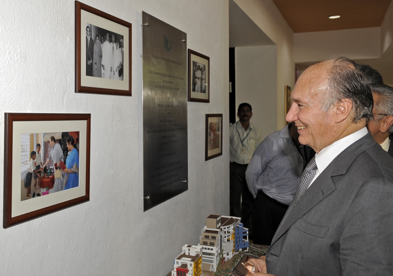 Mawlana Hazar Imam smiles as he looks at photographs of his visit to the Diamond Jubilee High School in 1958, and Princess Zahra’s inauguration of the new site of the school in 2007. 