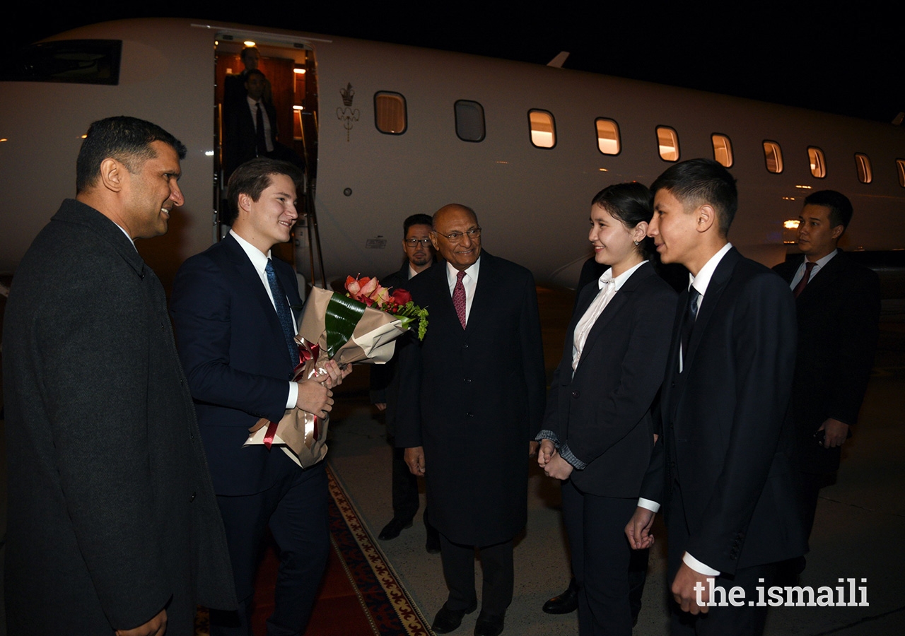 Prince Aly Muhammad is presented flowers by two students from the Aga Khan School in Osh upon his arrival in Kyrgyzstan.