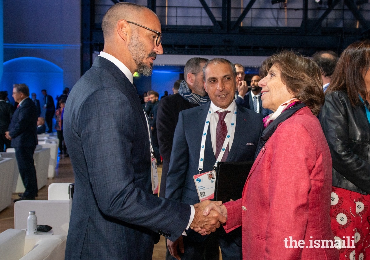 Catherine Colonna, Ministra da Europa e dos Negócios Estrangeiros de França, cumprimenta o Príncipe Rahim no Fórum de Paris para a Paz, enquanto Shamir Samdjee, Representante do Imamat Ismaili em França, observa.