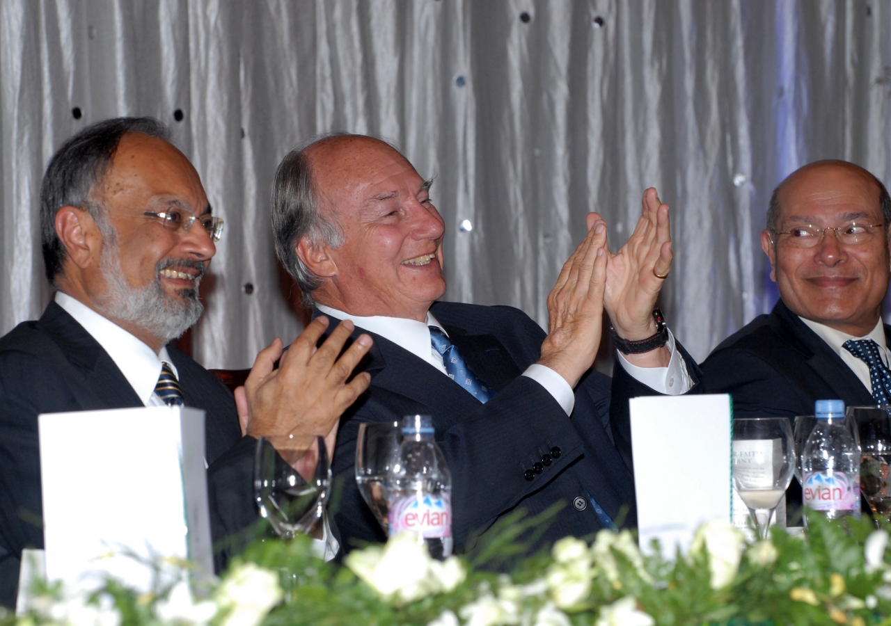 Mawlana Hazar Imam applauds during the institutional dinner, together with Ismaili Council President Aitmadi Zul Abdul and AKDN Resident Representative Aitmadi Aziz Bhaloo.