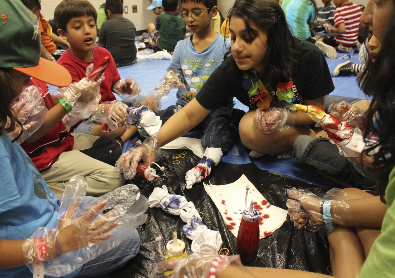 A counselor helps participants tie-die shirts during a self-expression activity at an Ismaili summer camp.