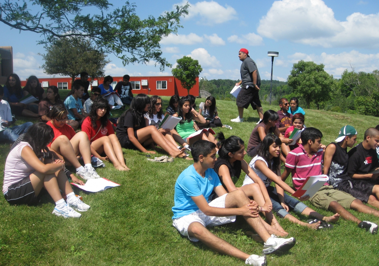 Seated on the lawn, participants sing the Al-Ummah brotherhood song together.