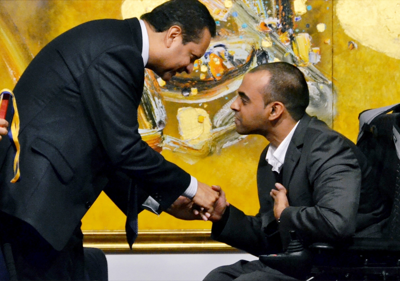 Paralympian and Disability Ambassador Ali Lalani receives a medal from President Amin Mawji of the Ismaili Council for the UK.