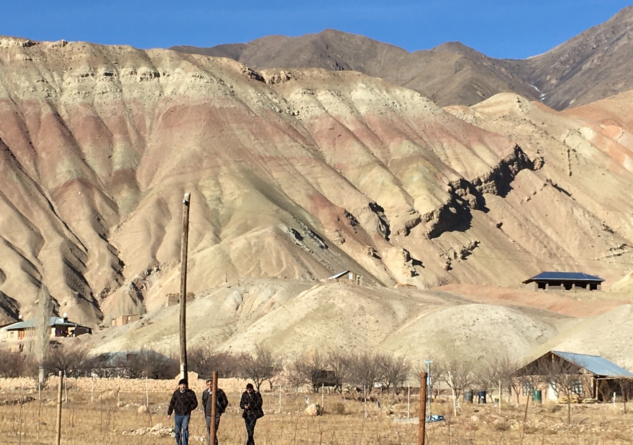 NGO team site visit to flat intensive farm land for apricots, apples, plums, potatoes and alfalfa fodder; surrounded by bare unstable geomorphological landscapes in Ayni district.