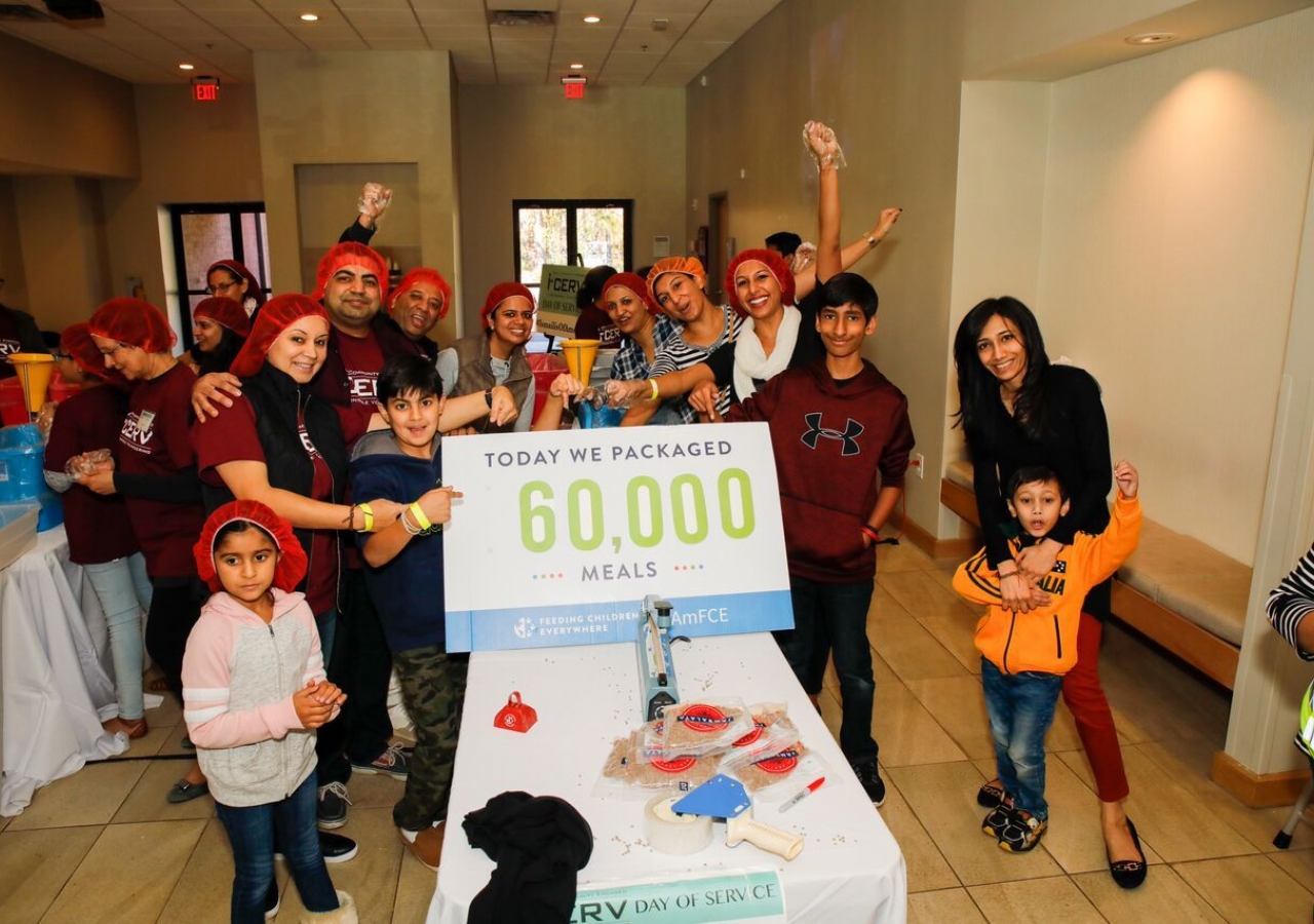 Volunteers of all ages celebrate as they exceed the goal of packing 60,000 meals in celebration of 60 years of Imamat.