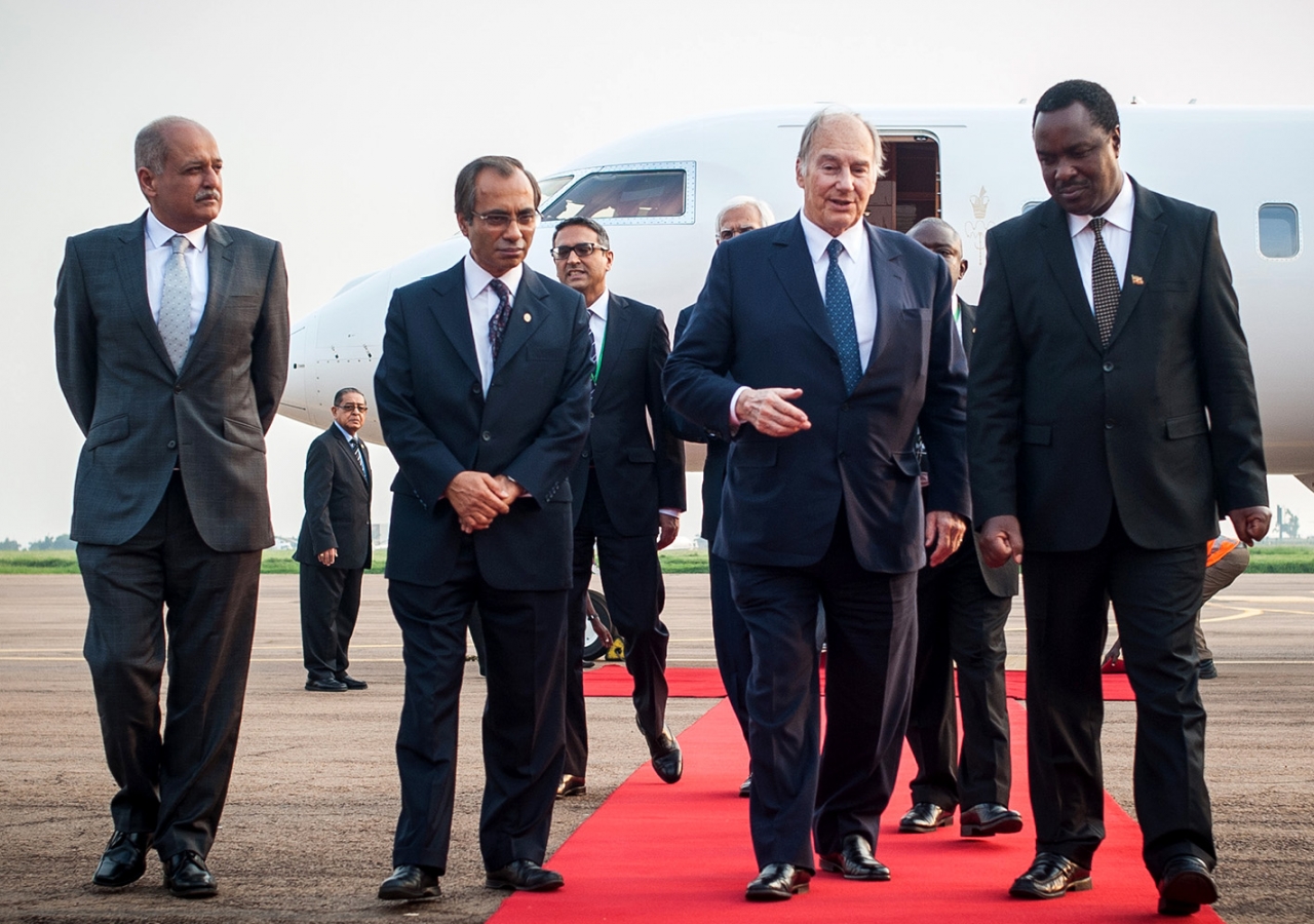 Ismaili Council President Minaz Jamal and AKDN Representative Mahmood Ahmed accompany Mawlana Hazar Imam and Minister Tumwesigye Elioda from the plane. AKDN / Will Boase