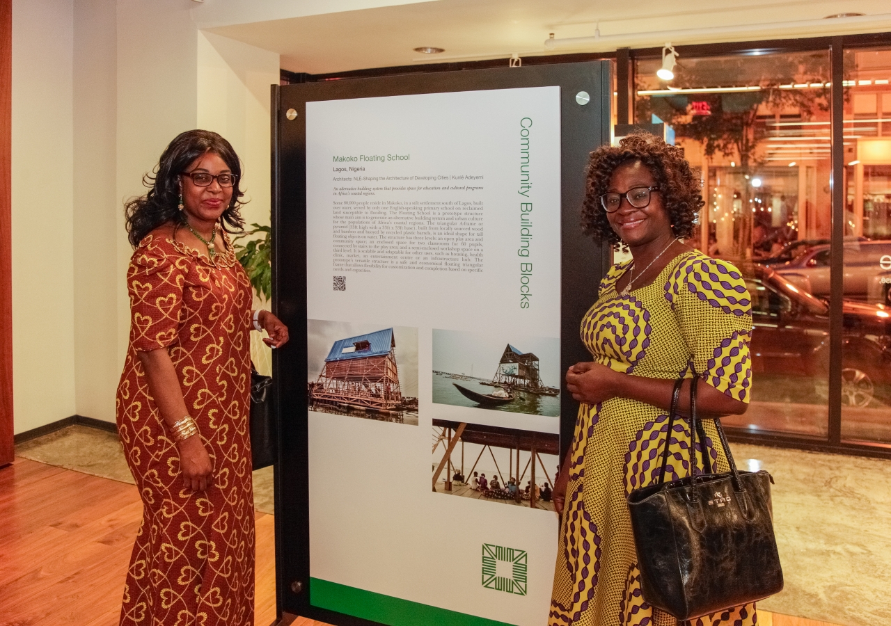 Ms. Fatima Elabor Ojiaku and Ms. Esther Gomo, of the Embassy of the Federal Republic of Nigeria stand alongside the Makoko Floating School in Lagos, Nigeria, an Award nominee. 