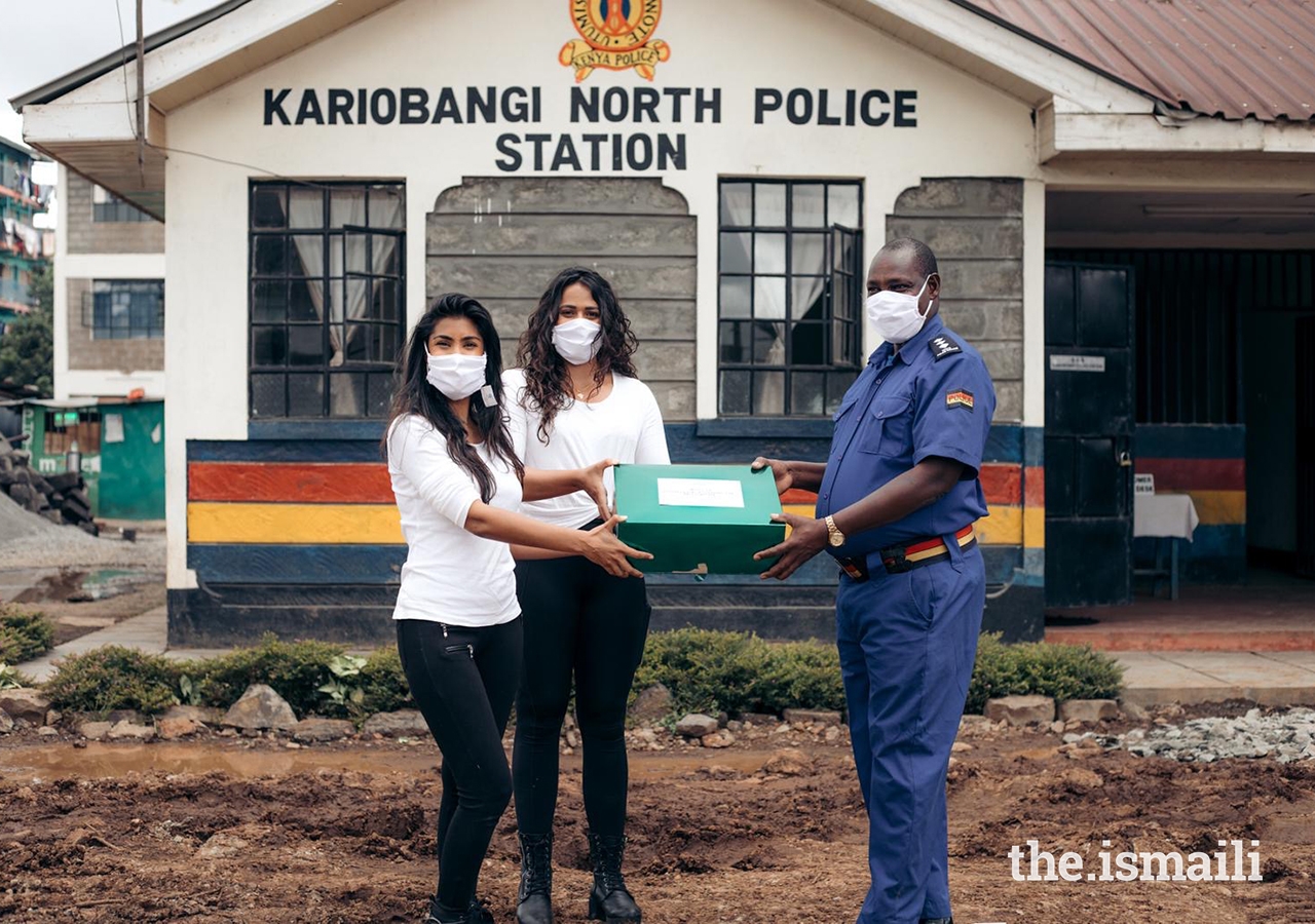 Alisha Popat and Talisa Lanoe present a box of masks to a representative from the Kariobangi North Police Station as part of their #TasksForMasks campaign.