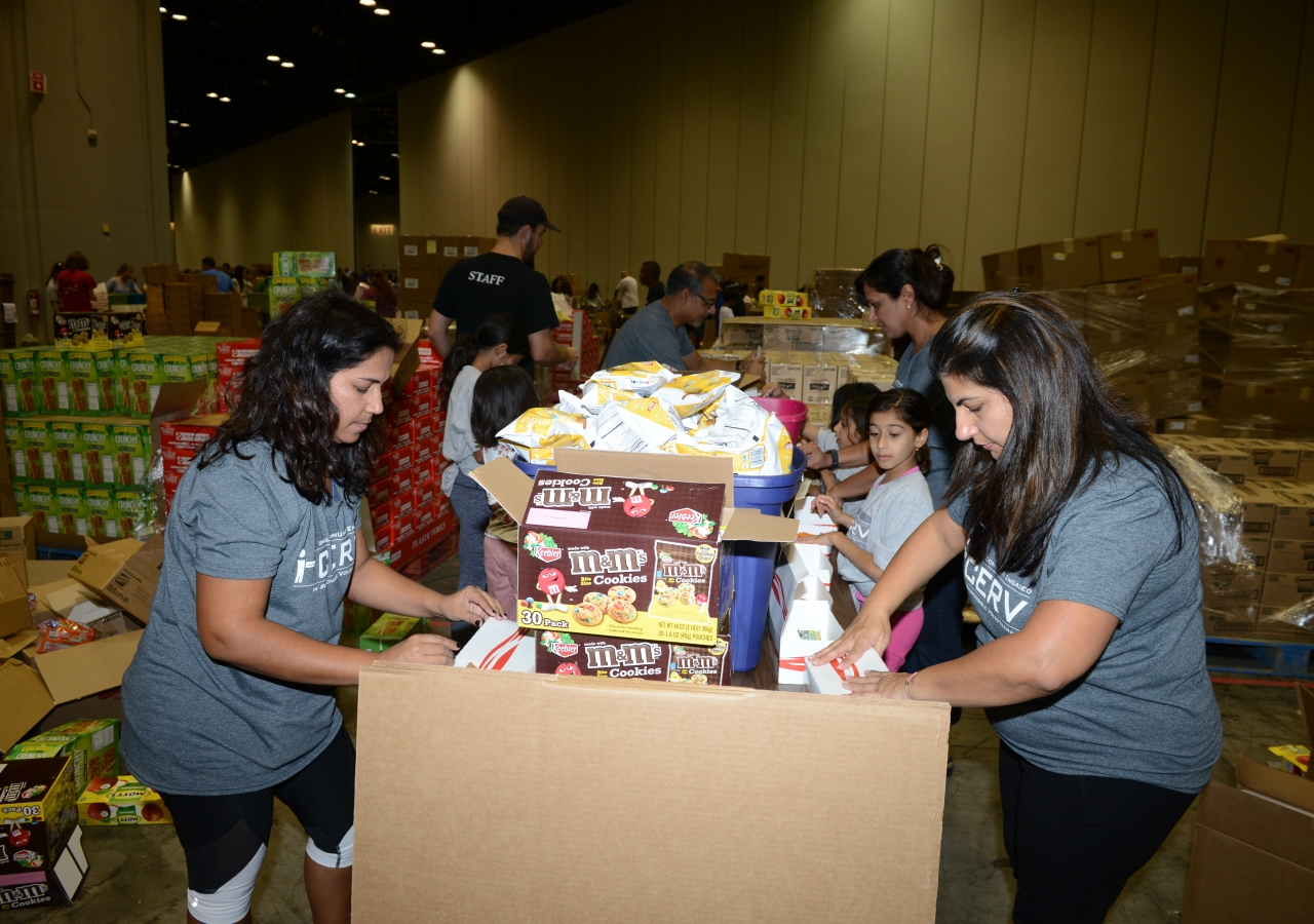 Members of the Florida Jamat assist in packing meals at the Orlando Convention Center to help victims of Puerto Rico.