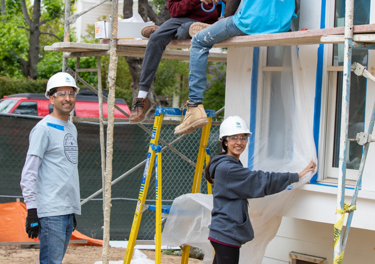 Boys love to climb. Here, Caleb and Kaden are perched on scaffolding and ready to attach siding, while Aliza and Naushad are firmly grounded. Photo: Nimmi Richards. 