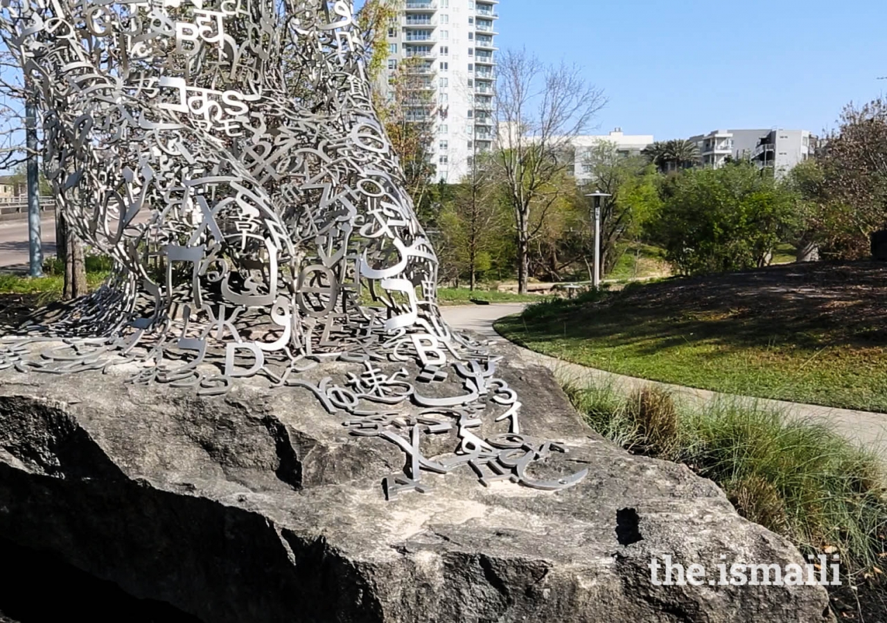 The sculptures are open-weave, metal structures that depict kneeling human forms, with characters and symbols from nine different languages.