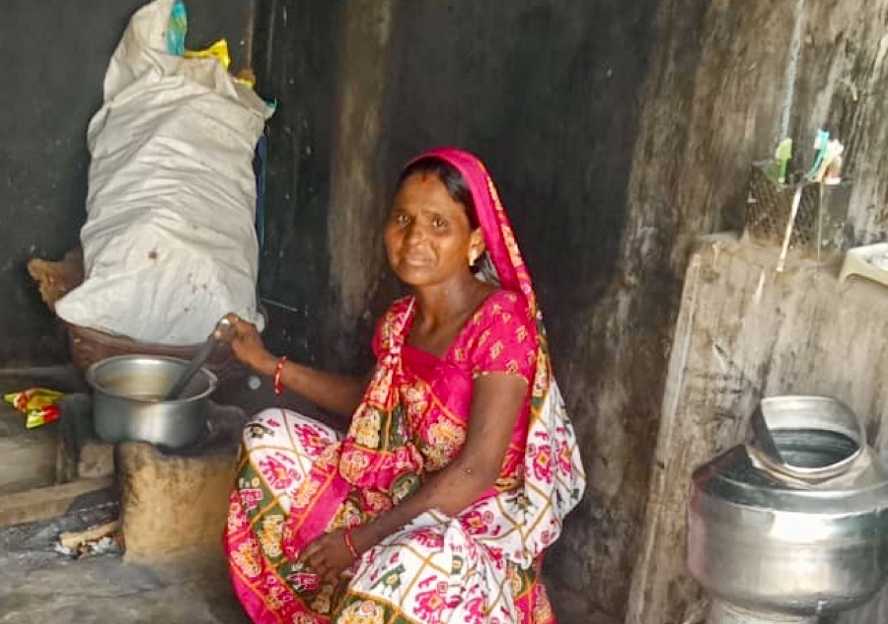 Village women skillfully cook meals in traditional saris using well-worn utensils.