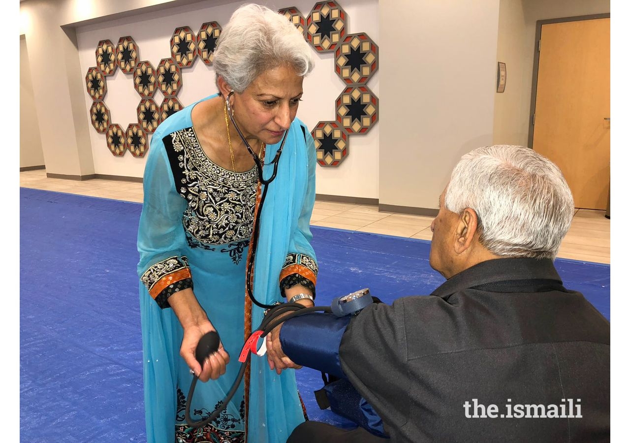 Dolly Bana checking the blood pressure of a Jamati member.