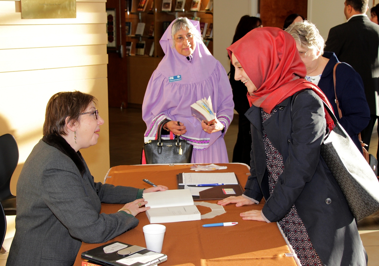 Carla Power signs a copy of her book for guests in attendance.