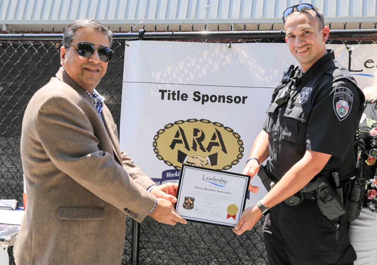 Chairman Suhel Kazani of Atlanta Retailers Association (ARA) with Officer Groins of Johns Creek receiving a plaque for ARA’s support of the ARA K-9 Training Facility.