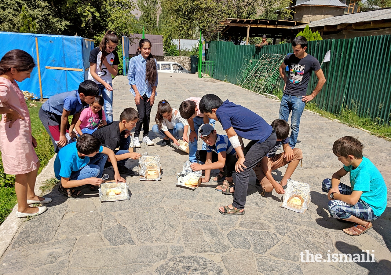 Students harness the power of the sun in their solar ovens to melt cheese on bread.