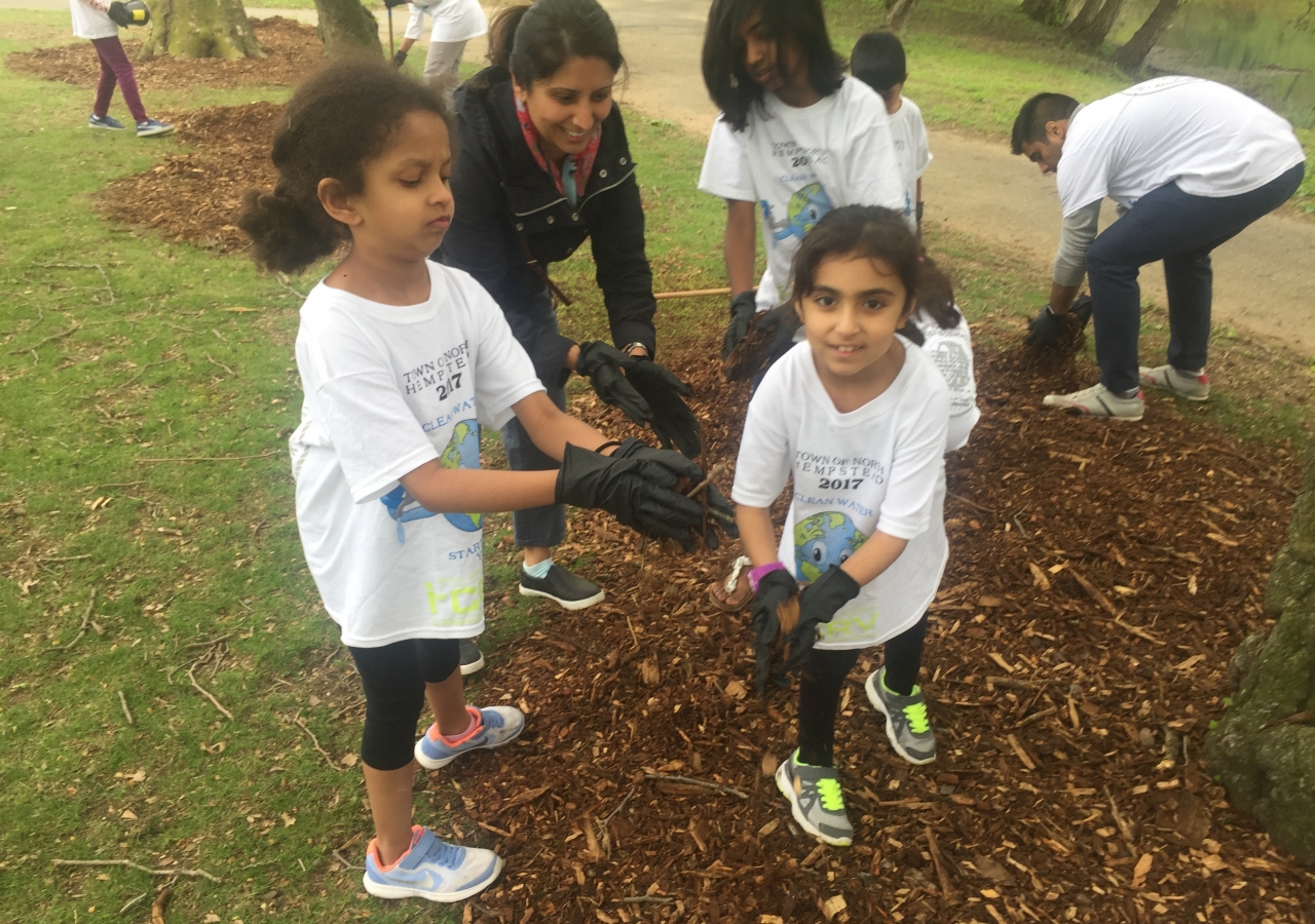 Young I-CERV volunteers spreading mulch along the base of trees to help conserve soil moisture and improve soil fertility.