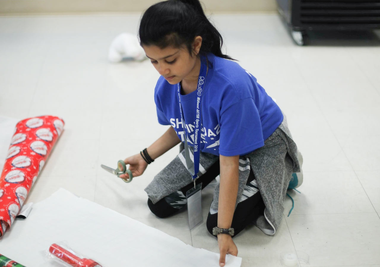 Alyssa Merchant takes a break from playing basketball to wrap a toy to donate during the I-CERV Wrap-A-Thon.