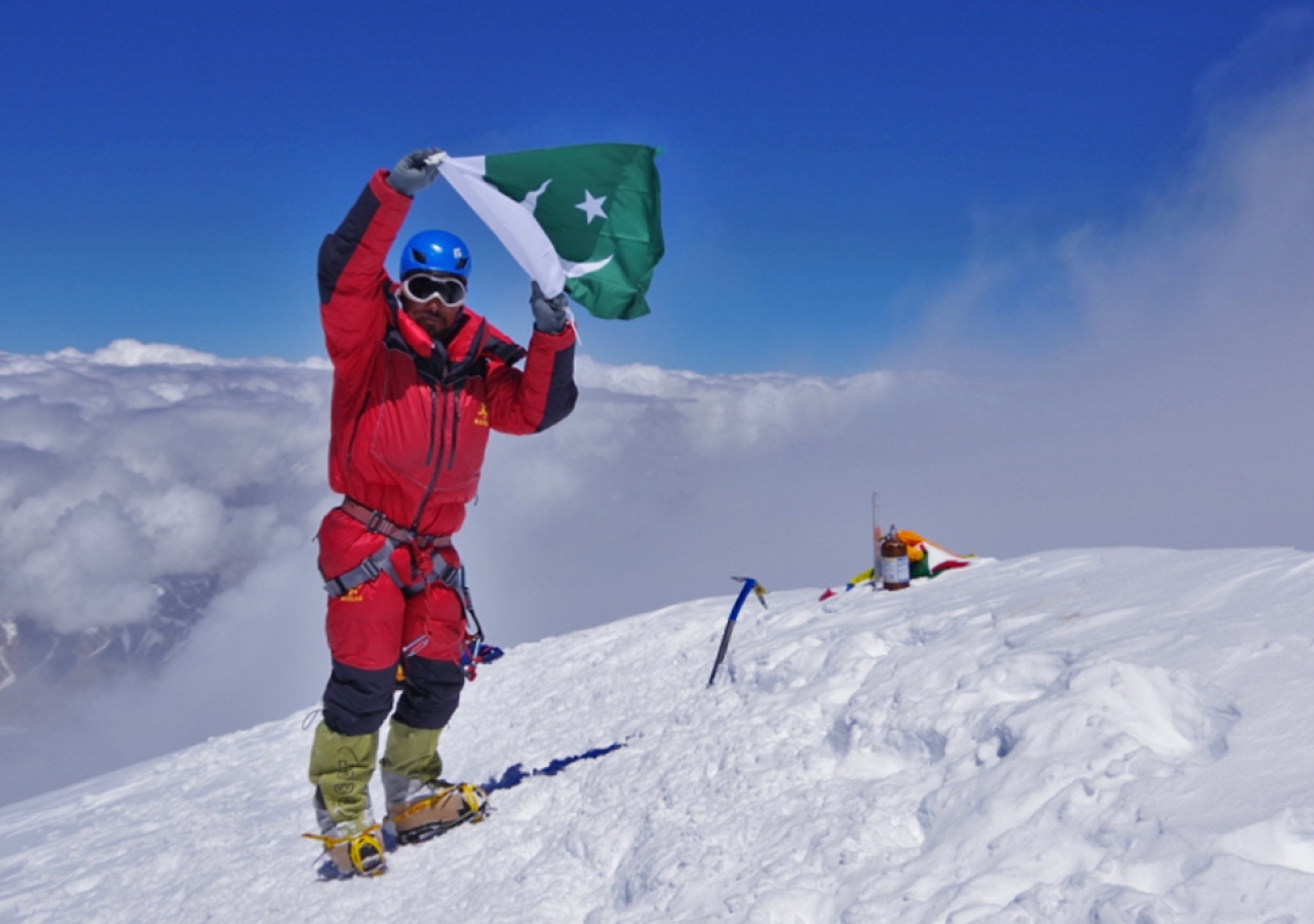 Sirbaz Khan displays the flag of Pakistan after reaching the top of K2.