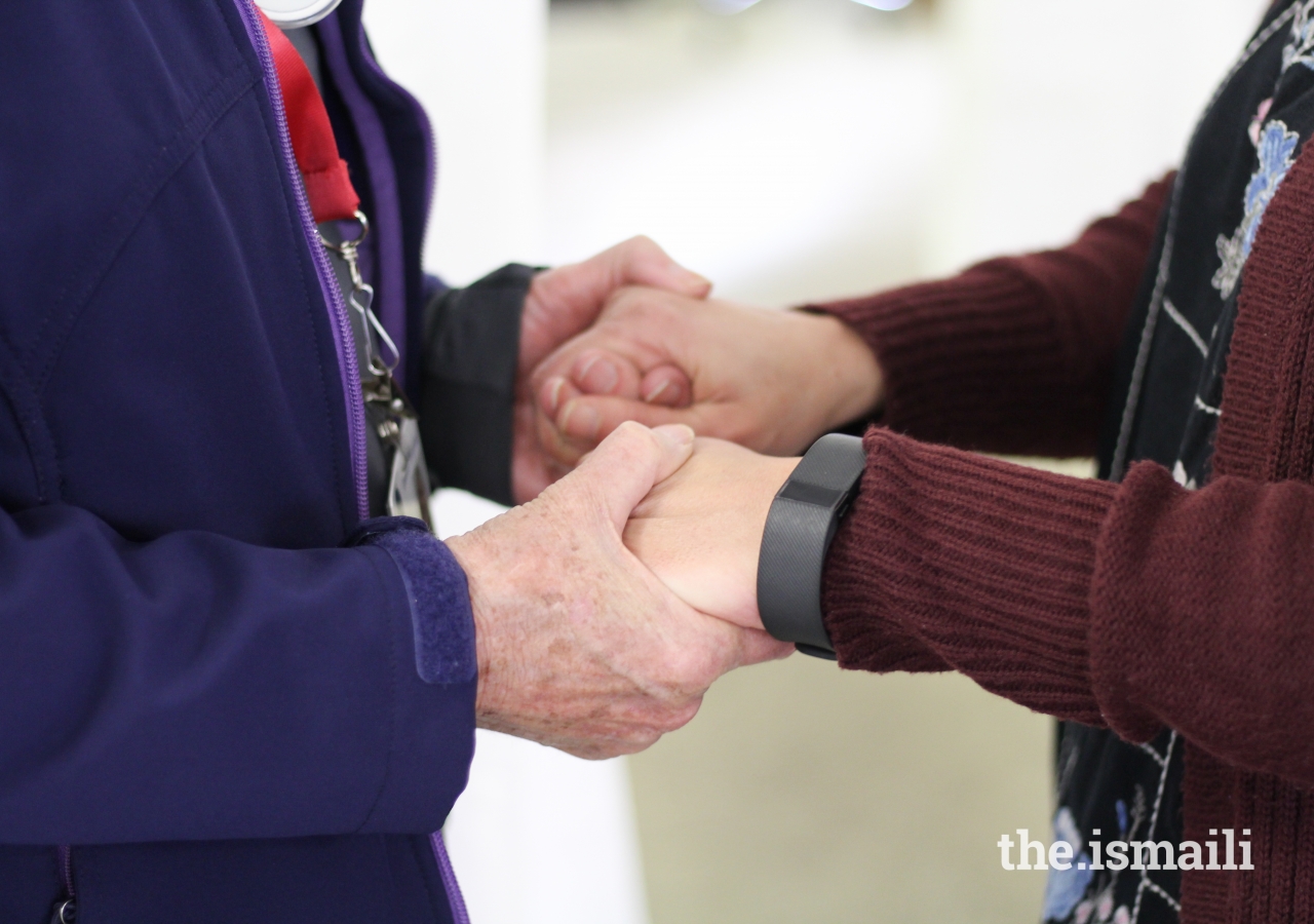 A Red Cross volunteer holds hands with AKU nurse Amina Huda.