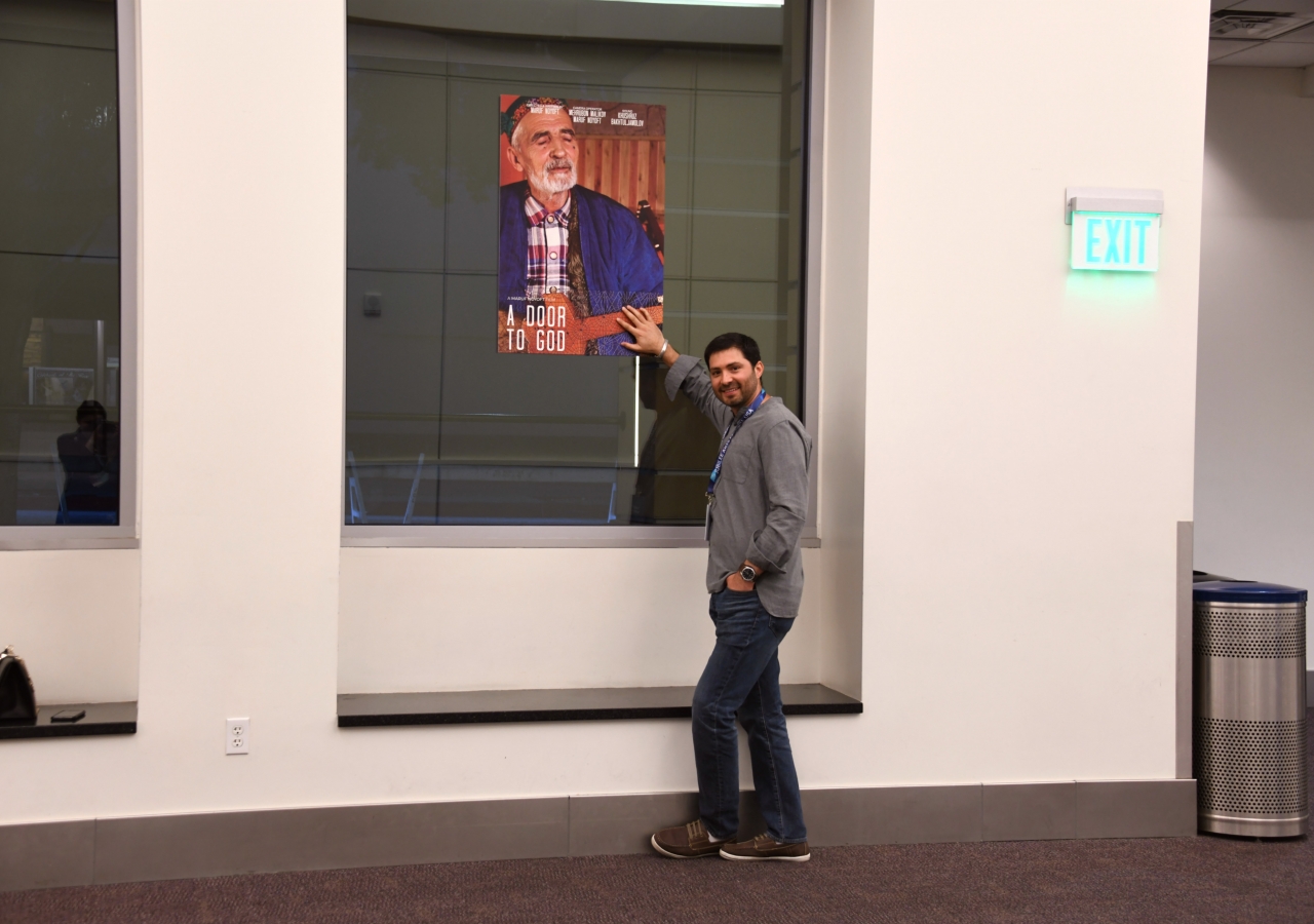 Maruf Noyoft next to a poster of his film, "A Door to God."