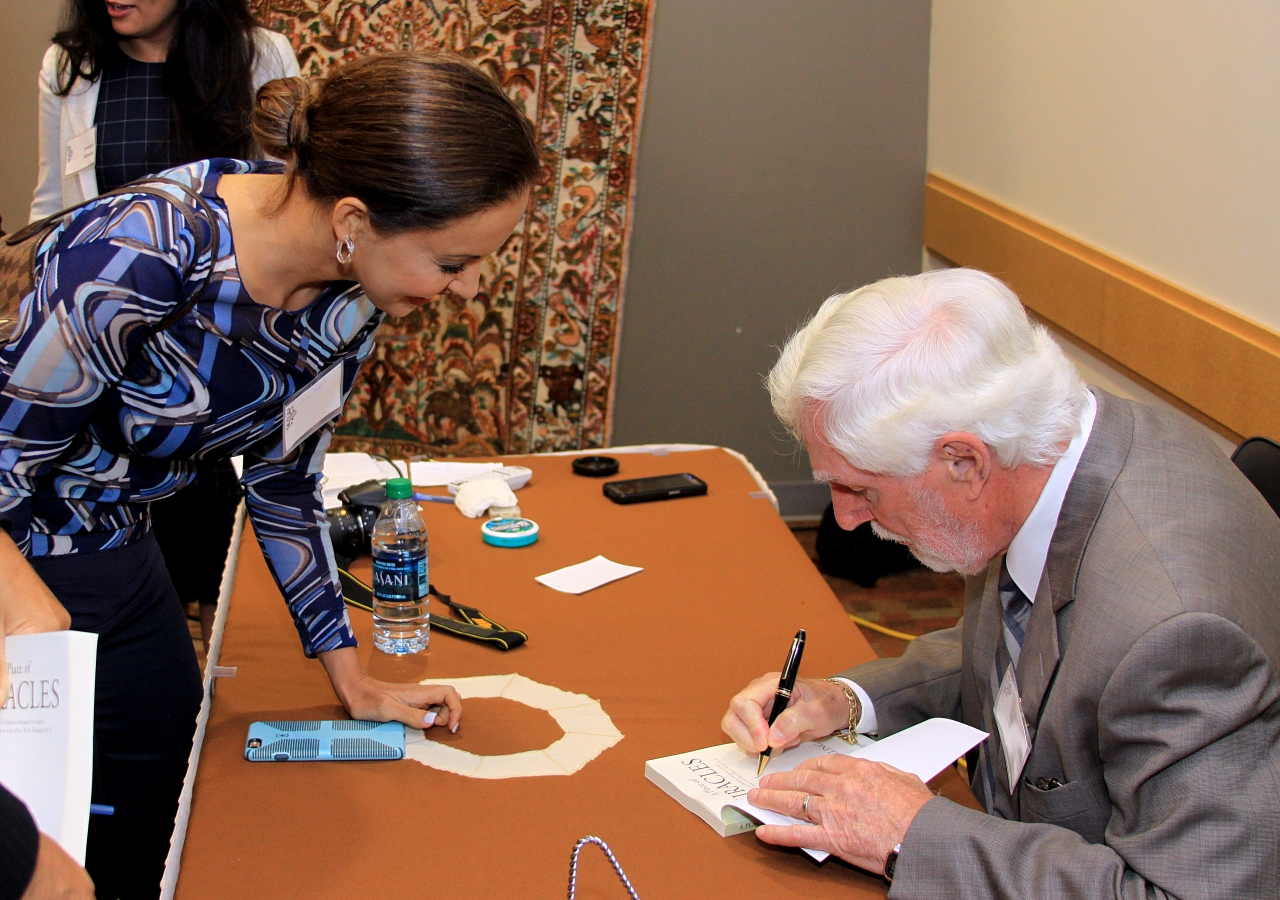 Lee Hilling, Chairman of the FMIC signing a book for a guest at Ismaili Jamatkhana, Plano.