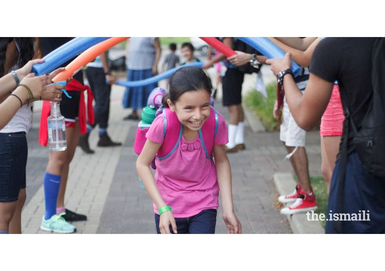 Walking through a tunnel of noodles, a participant smiles as she walks to her parents.