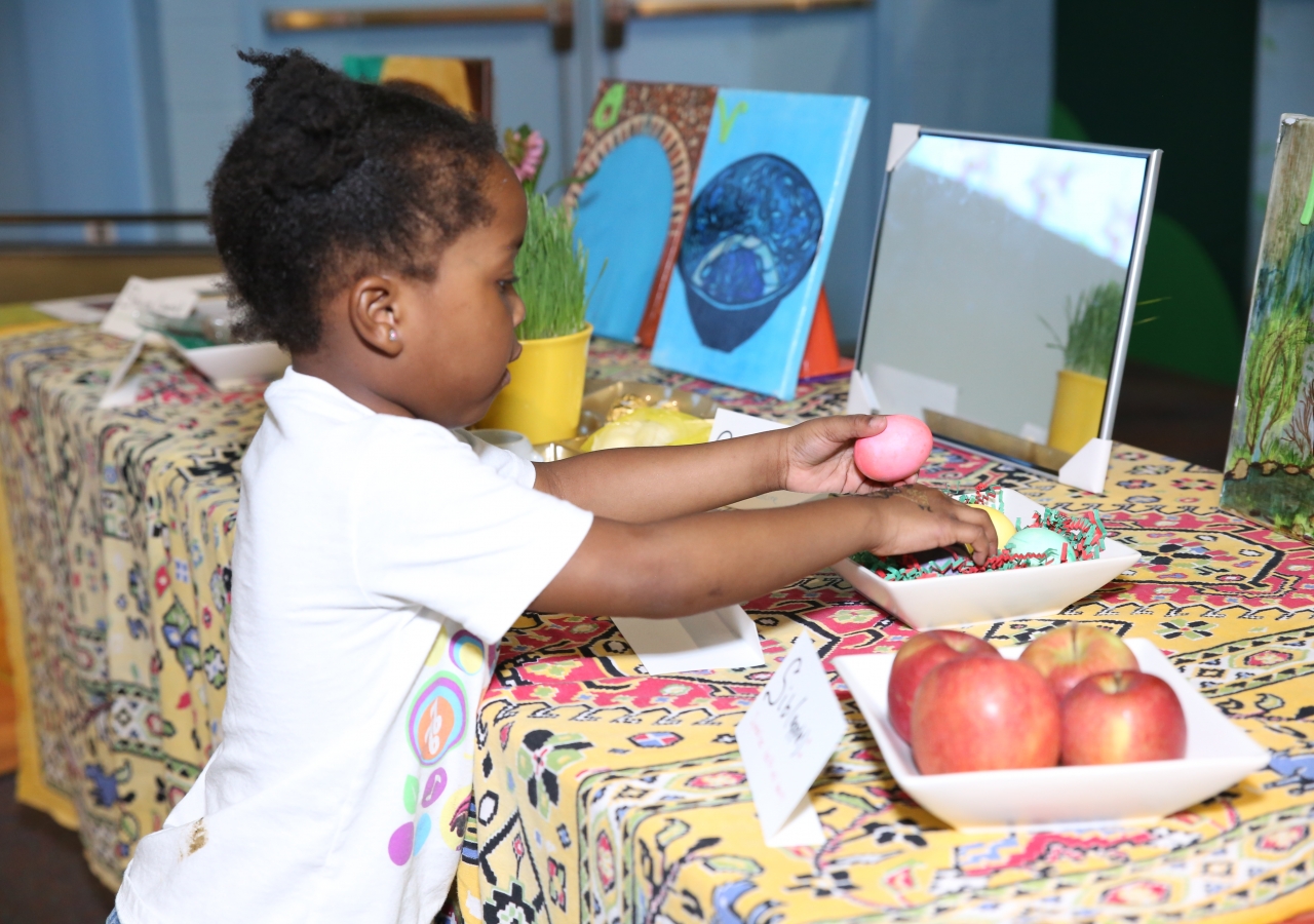 A young child plays with items on the Haft-Seen table display at the Children's Museum in Atlanta.