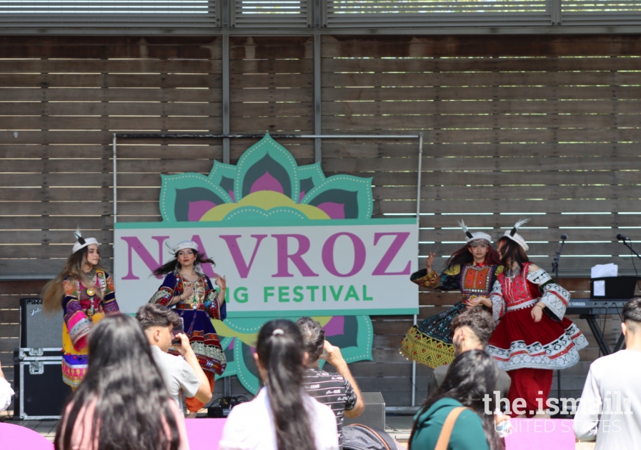 Dancers performing a Pashtun dance on the stage in traditional Afghan costumes.