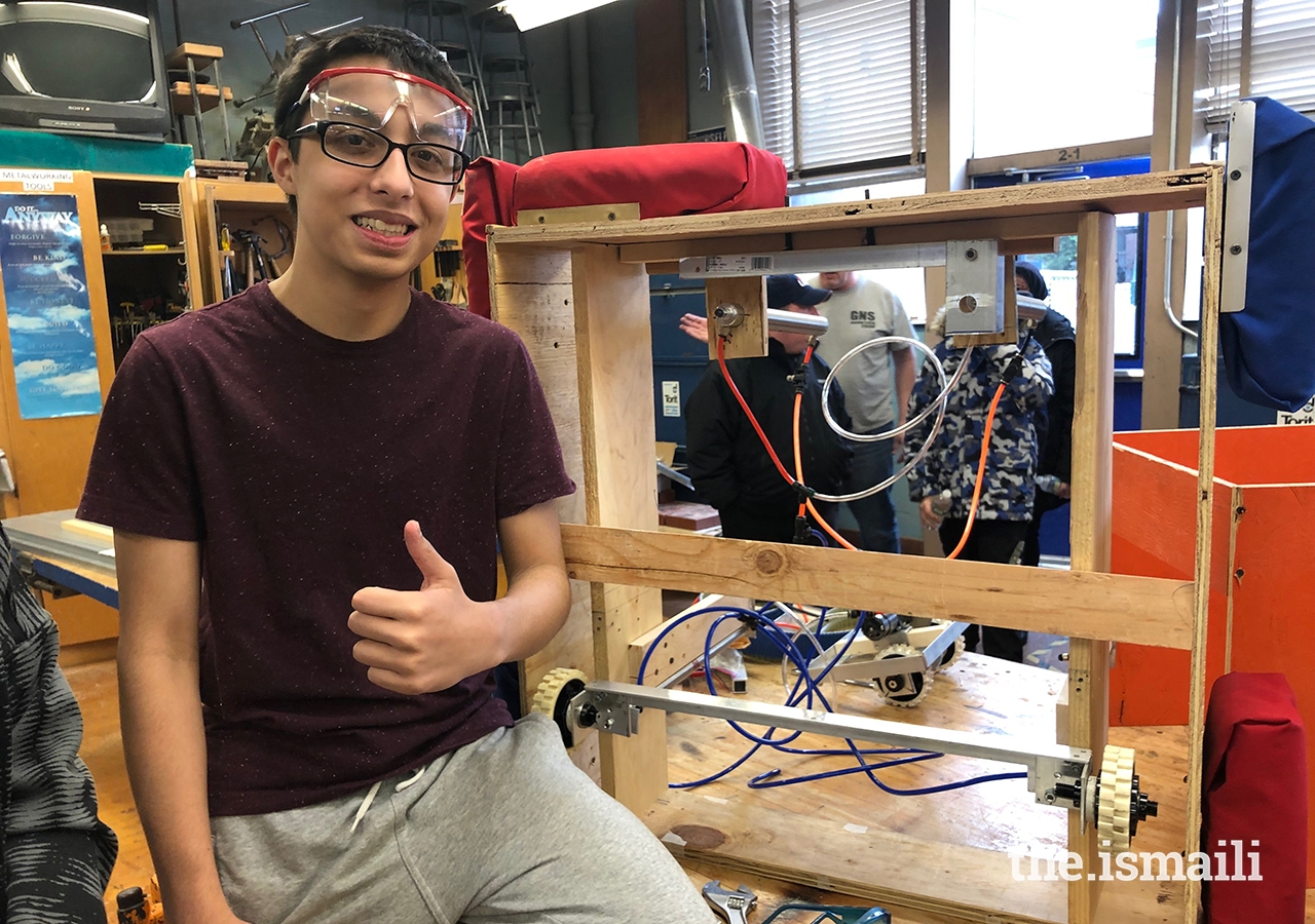 Saif Punjwani standing next to the prototype of his FIRST Robotics Competition team's lift mechanism. Saif led the creation of the lift mechanism, which was a crucial component that allowed his team's 2019 robot to lift above the ground and reach a new level. 