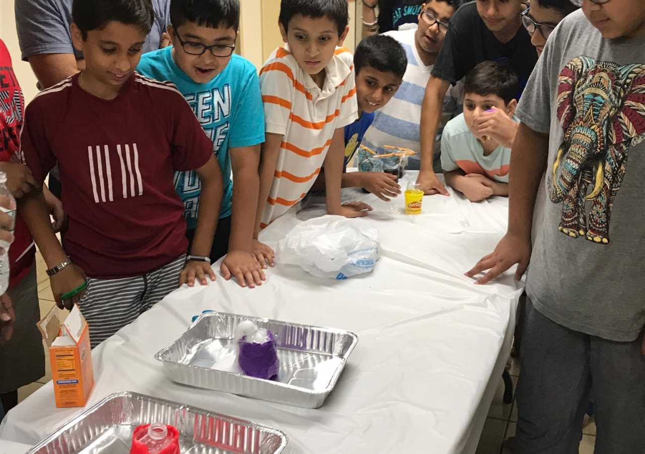 Participants observe as they begin to experiment with chemical reactions in their model volcanoes. 