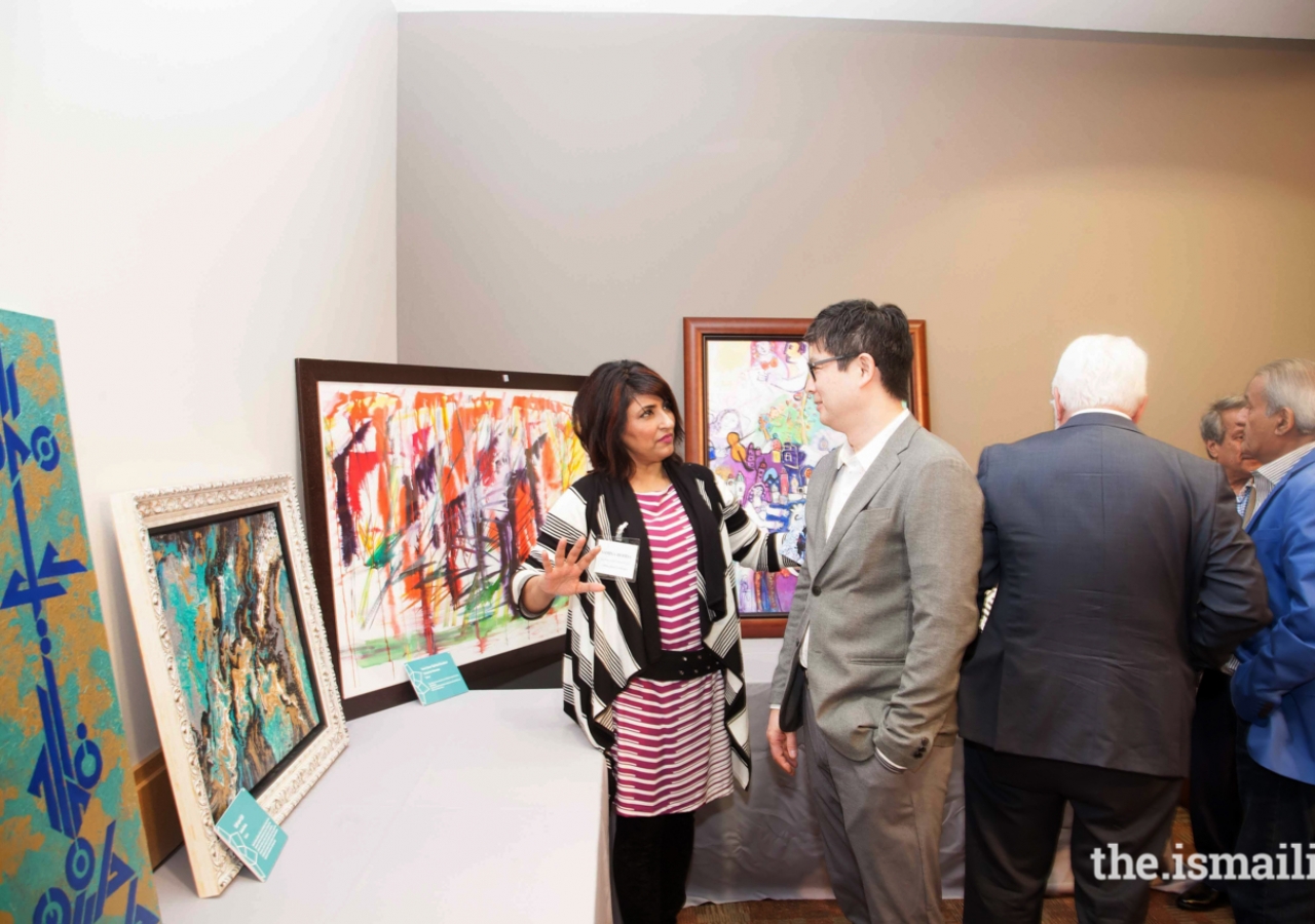 Samina Hooda showing a guest some of the artwork exhibited at the Jubilee Arts Festival.