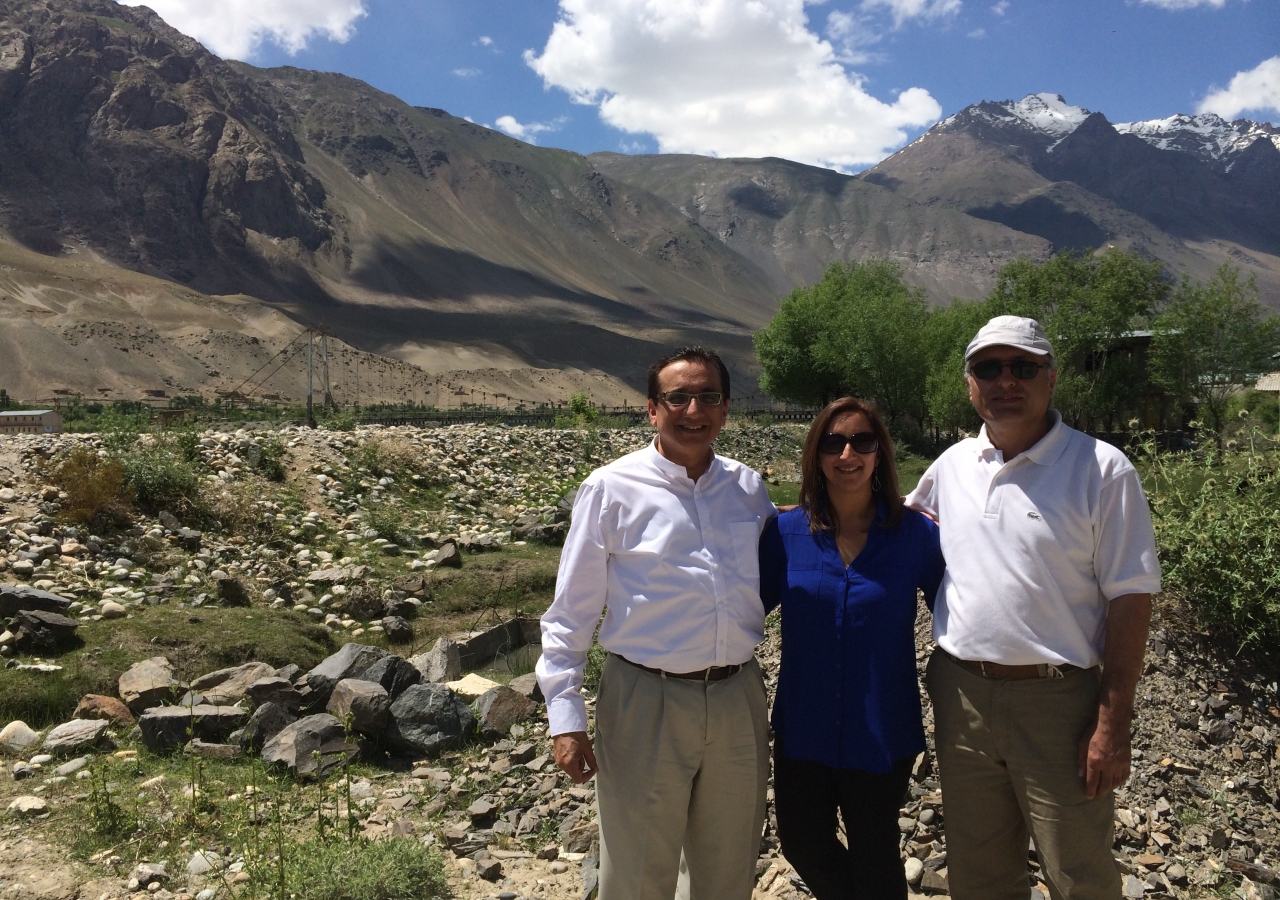 Dr. Talib (center) with Dr. Alibek, a local surgeon (left), and AKHB Chair Dr. Mirza Kajani (right) in Khorog, Tajikistan. Behind them is a cross-border bridge to Afghanistan, built by AKDN to reach the remote and isolated Jamats across Afghanistan.