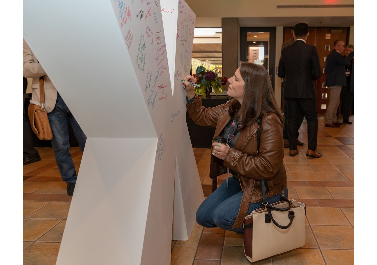 Attendees signing a large “X” with positive messages while networking and awaiting the presentations by speakers at the TEDxSugarLand.