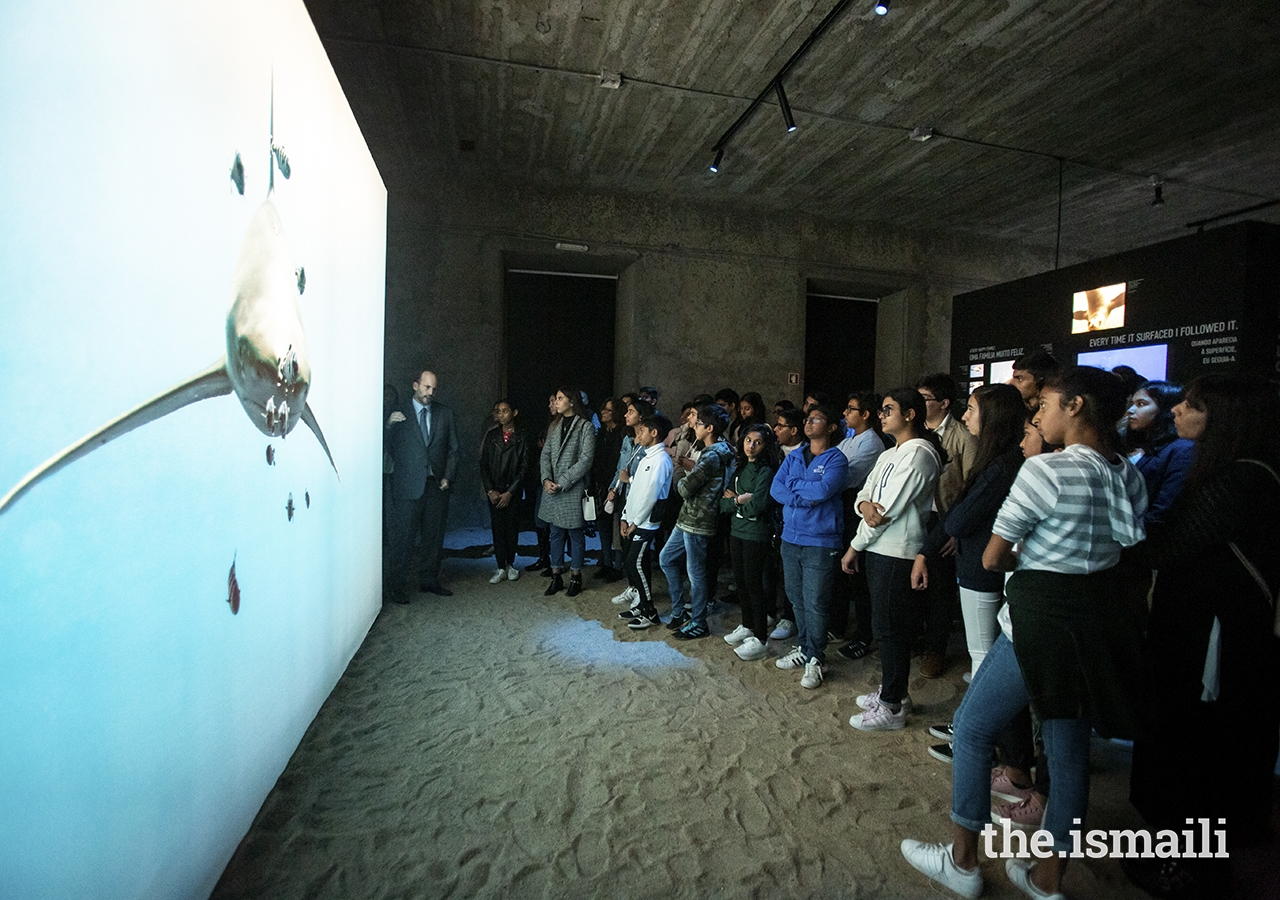 Students listen as Prince Hussain explains the story behind a photo of a shark at The Living Sea photo exhibition in Lisbon.