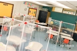 View of a classroom with desk partitions to separate students.