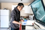 Rahim Bhimani uses the industrial laser cutting machine in his basement to create thousands of face shields for healthcare workers. 