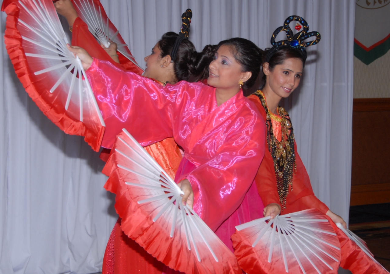 Youth from the Jamat perform a dance before Mawlana Hazar Imam, featuring colourful paper fans. 