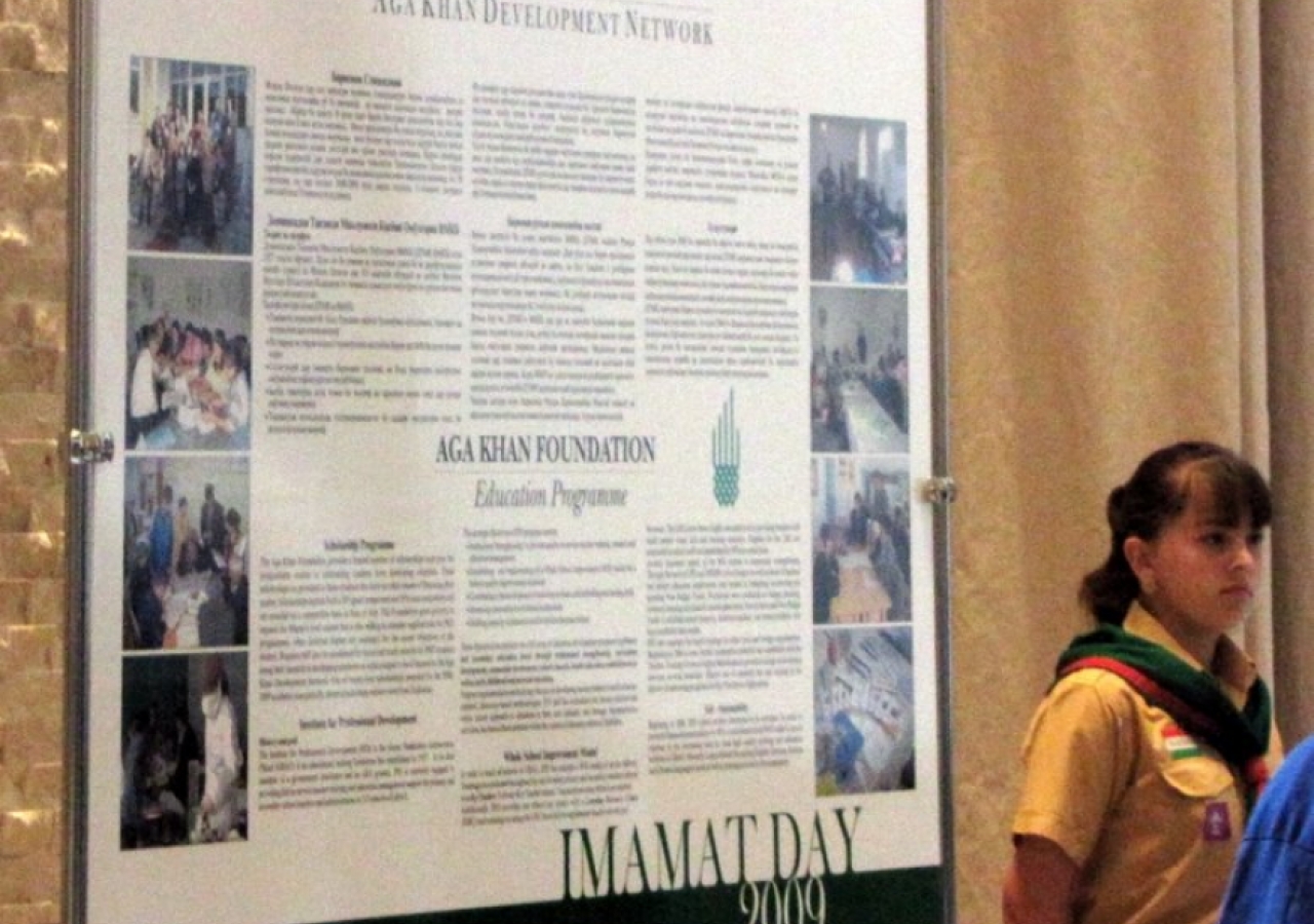 An Aga Khan Scout stands next to one of the educational display boards at the Imamat Day Reception.