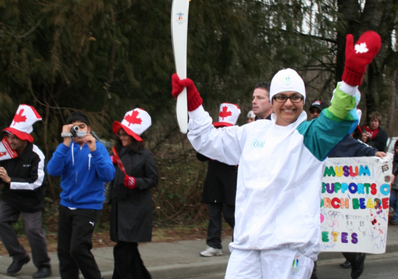 Razia Esmail waves at onlookers as she caries the Olympic flame in Chilliwack, British Columbia.