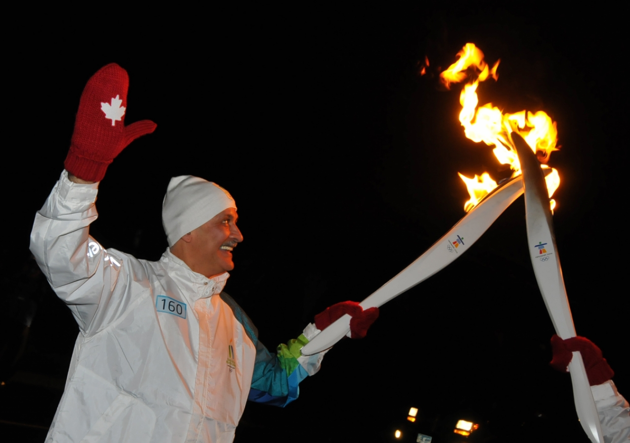 In a kiss of torches, Salim Ahmed receives the Olympic flame in Abbotsford, British Columbia.