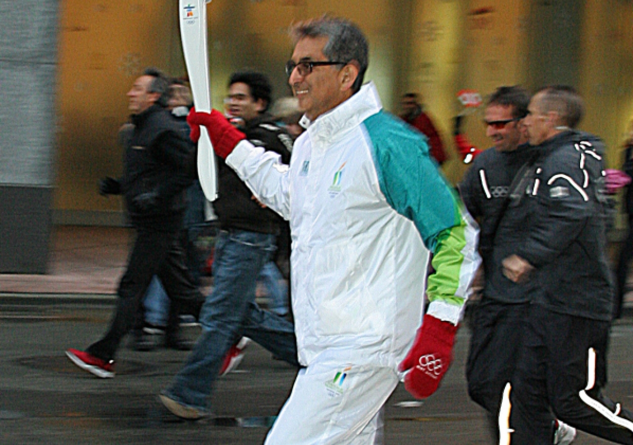 Nadir Mohamed, who received the Olympic flame from Walter Gretzky, runs with the torch relay in Vancouver.