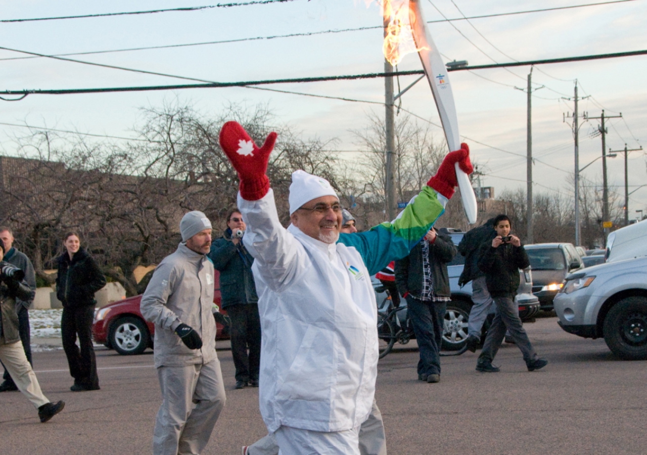 Ismaili Council for Canada President Mohamed Manji waves to the crowd, as he carries the Olympic torch on behalf of Ismailis across the country.