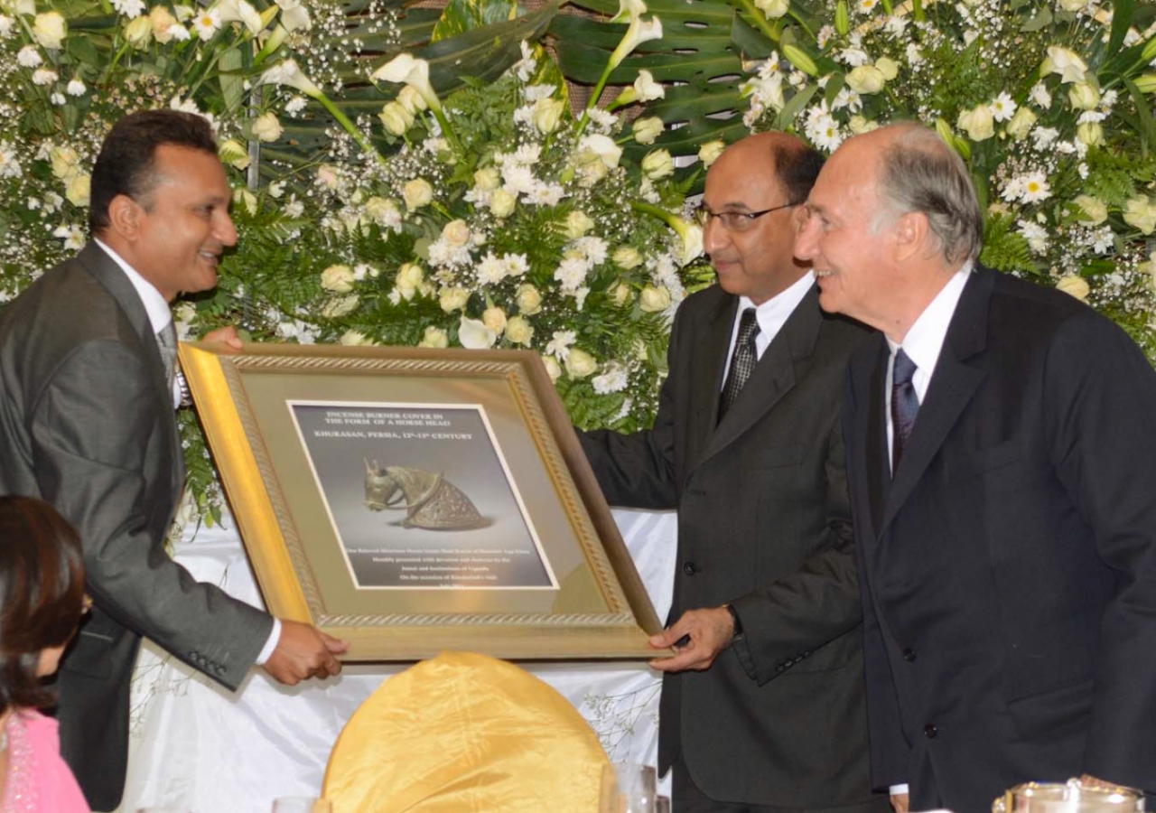 At the Uganda institutional leadership dinner, Mawlana Hazar Imam is presented with a gift of an incense burner cover from Khorasan shaped in the form of a horse head, on behalf of those gathered.