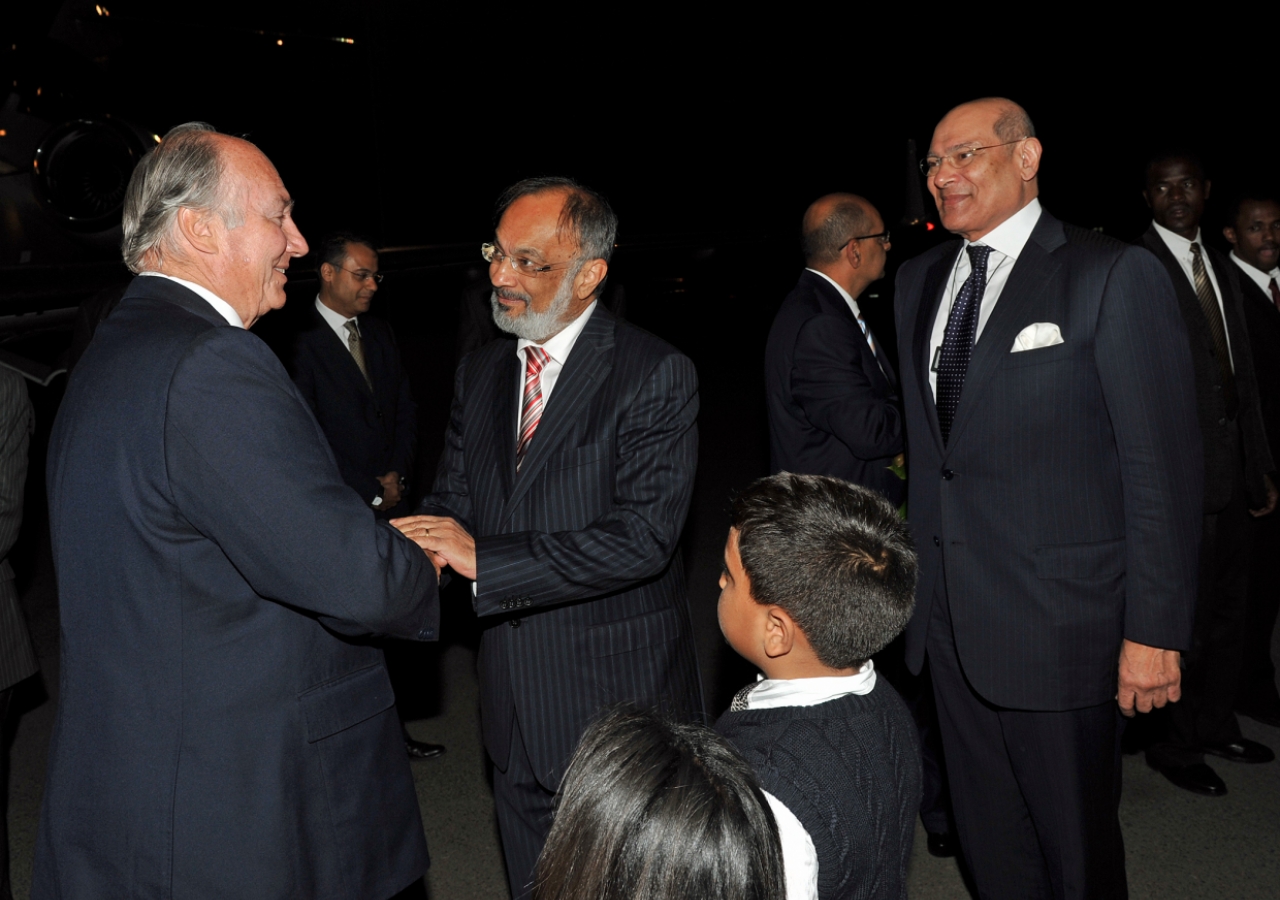 Mawlana Hazar Imam is greeted in Nairobi by Aitmadi Zul Abdul, President of the Ismaili Council for Kenya, and Aitmadi Aziz Bhaloo, Resident Representative of the Aga Khan Development Network in Kenya.