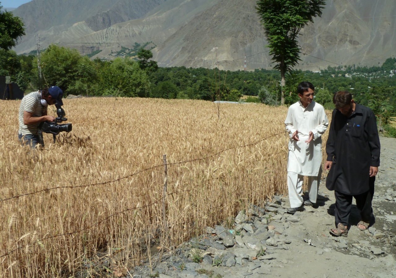 Jehangir of the Aga Khan Rural Support Programme is seen talking to one of the beneficiaries whose land was completely destroyed after the floods. The land was reclaimed by AKRSP and he has been able to harvest wheat on it. Cameraman Muhammed Usman is see